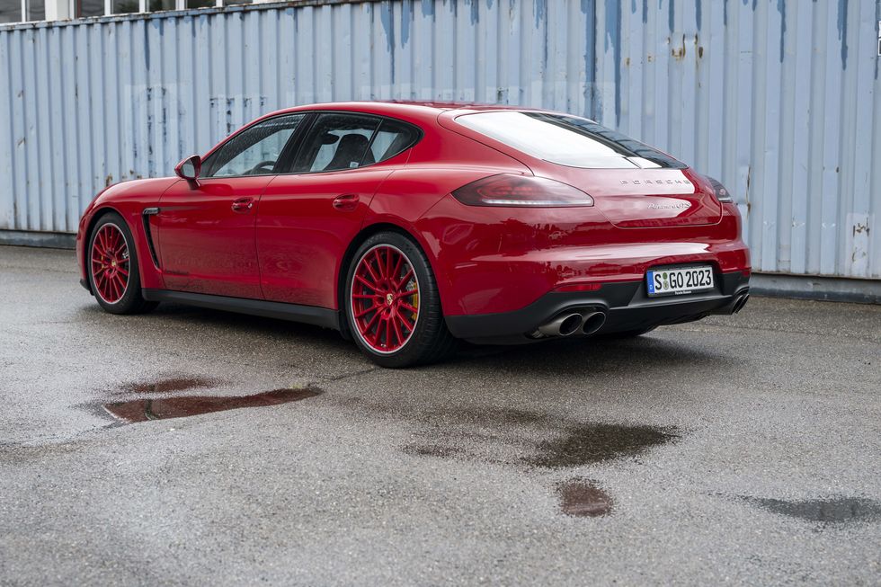 a red car parked in front of a white fence