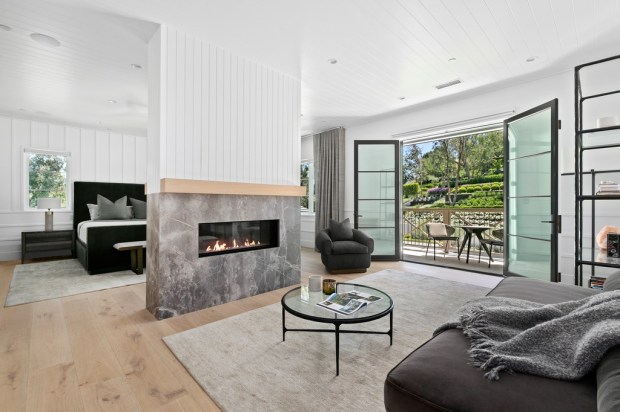 A fireplace divides the primary bedroom from a sitting area.(Photo...