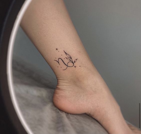 Capricorn zodiac symbol with leaves tattoo on the ankle