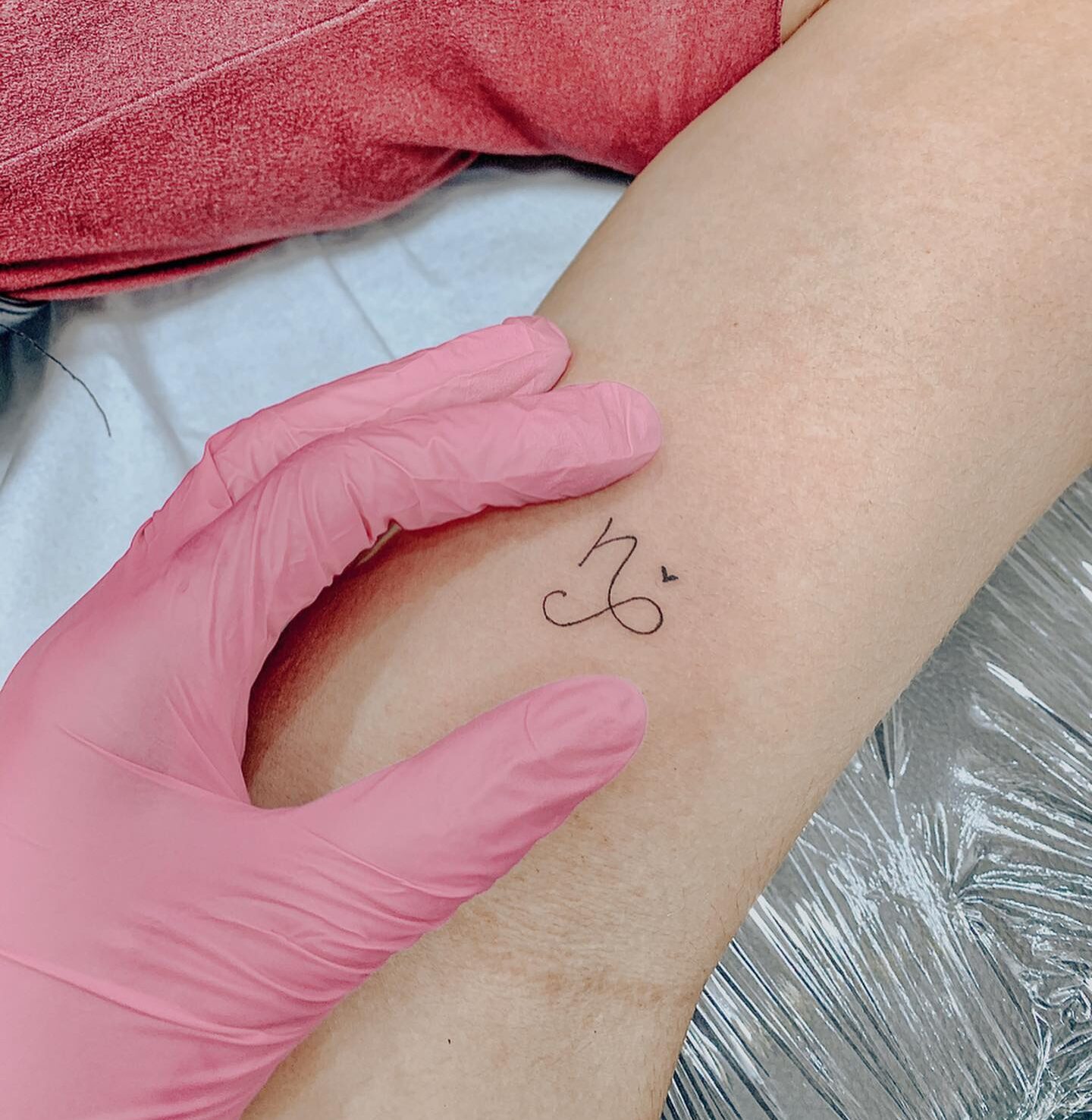 Minimalist Capricorn zodiac symbol and tiny heart tattoo on the inner arm