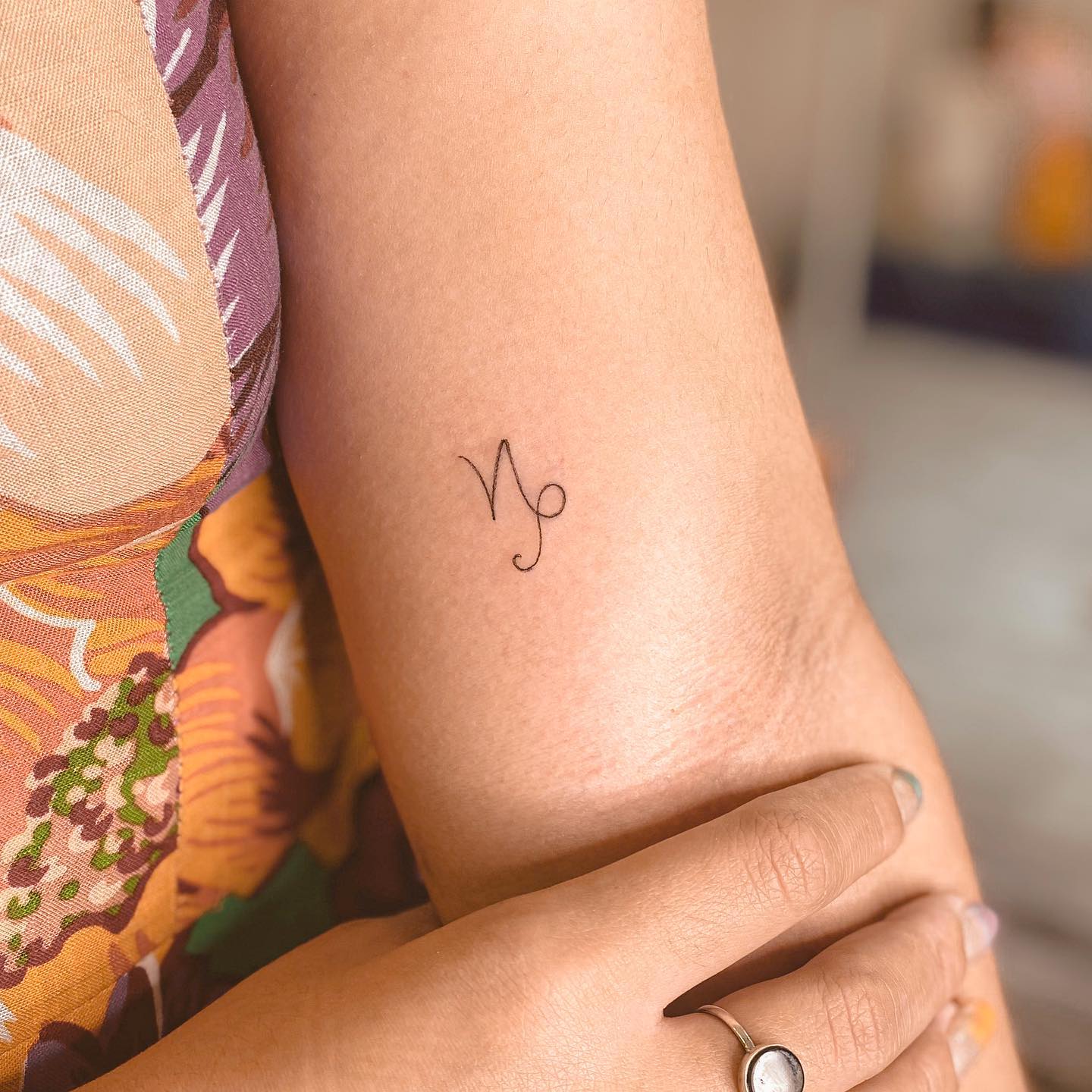 Minimalist Capricorn zodiac symbol tattoo on the inner arm