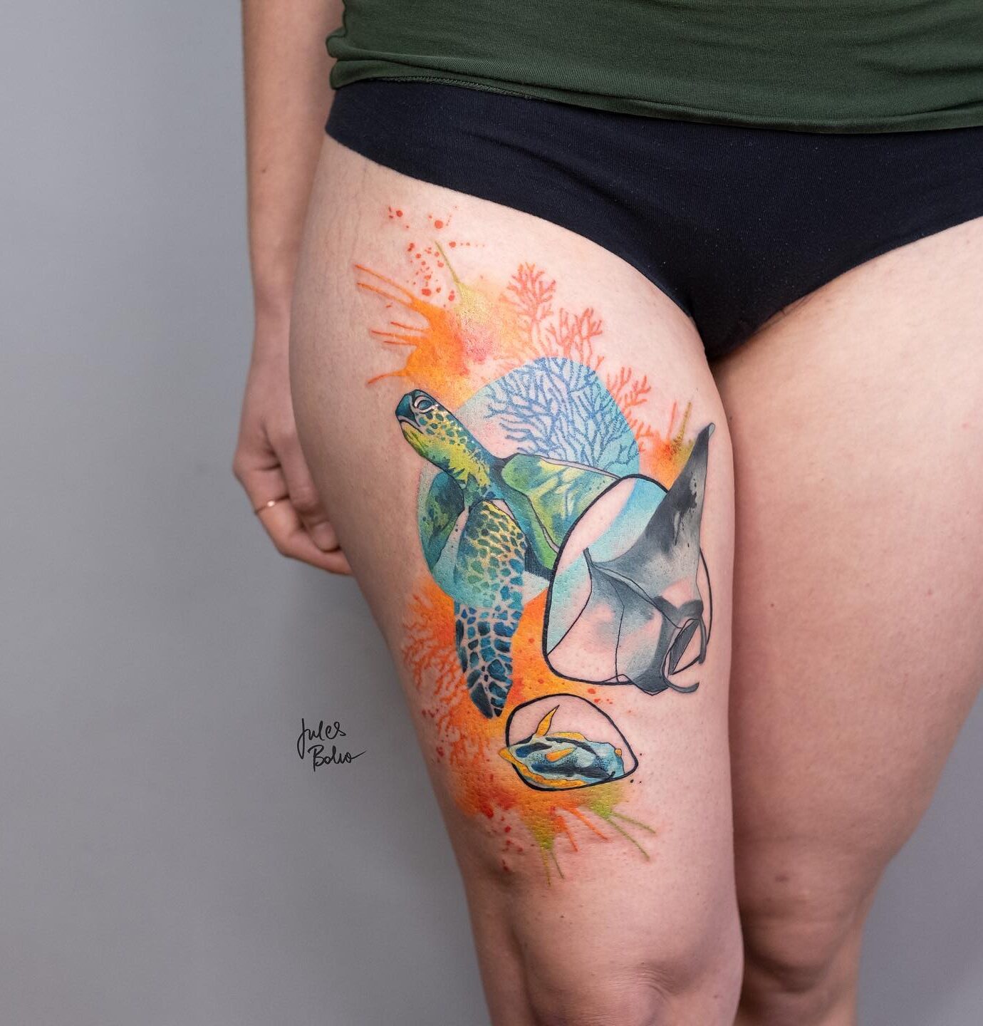 Colorful turtle, fish, and corals tattooed on the thigh