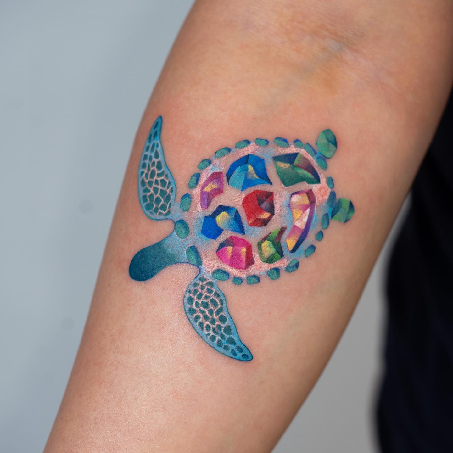 Watercolor style turtle tattoo on the inner forearm