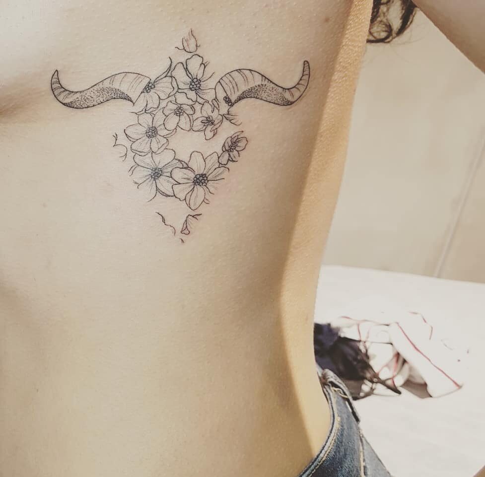 Horn and flowers tattoo located on the rib