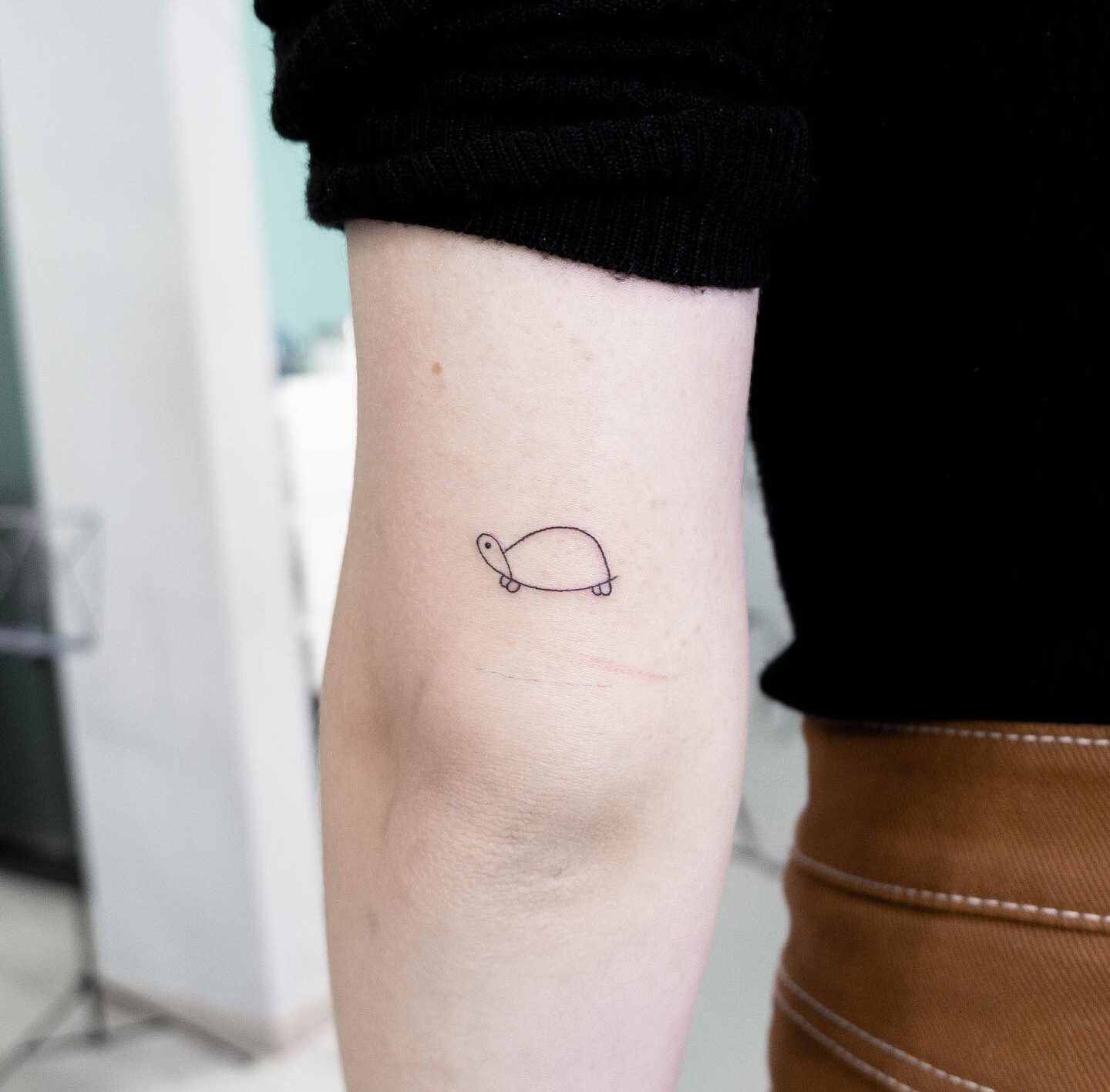 Minimalistic turtle tattoo on outer arm