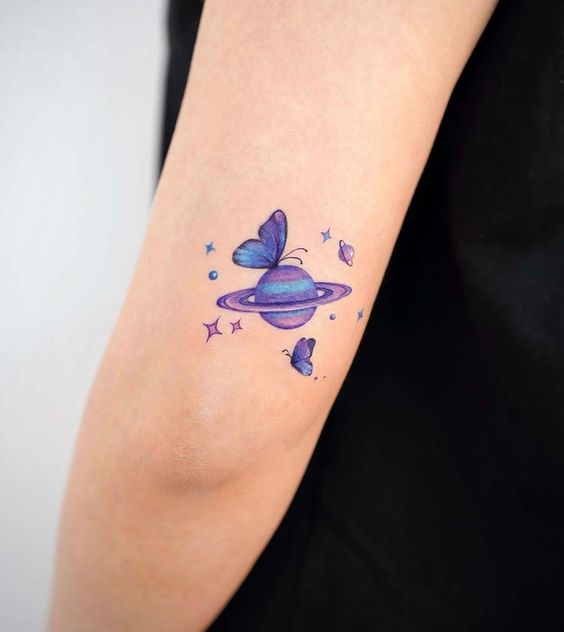Purple inked planet Saturn and butterfly tattooed on the outer arm