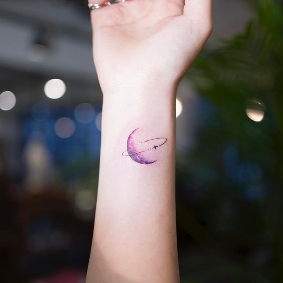 Purple inked planet Saturn tattooed on the wrist