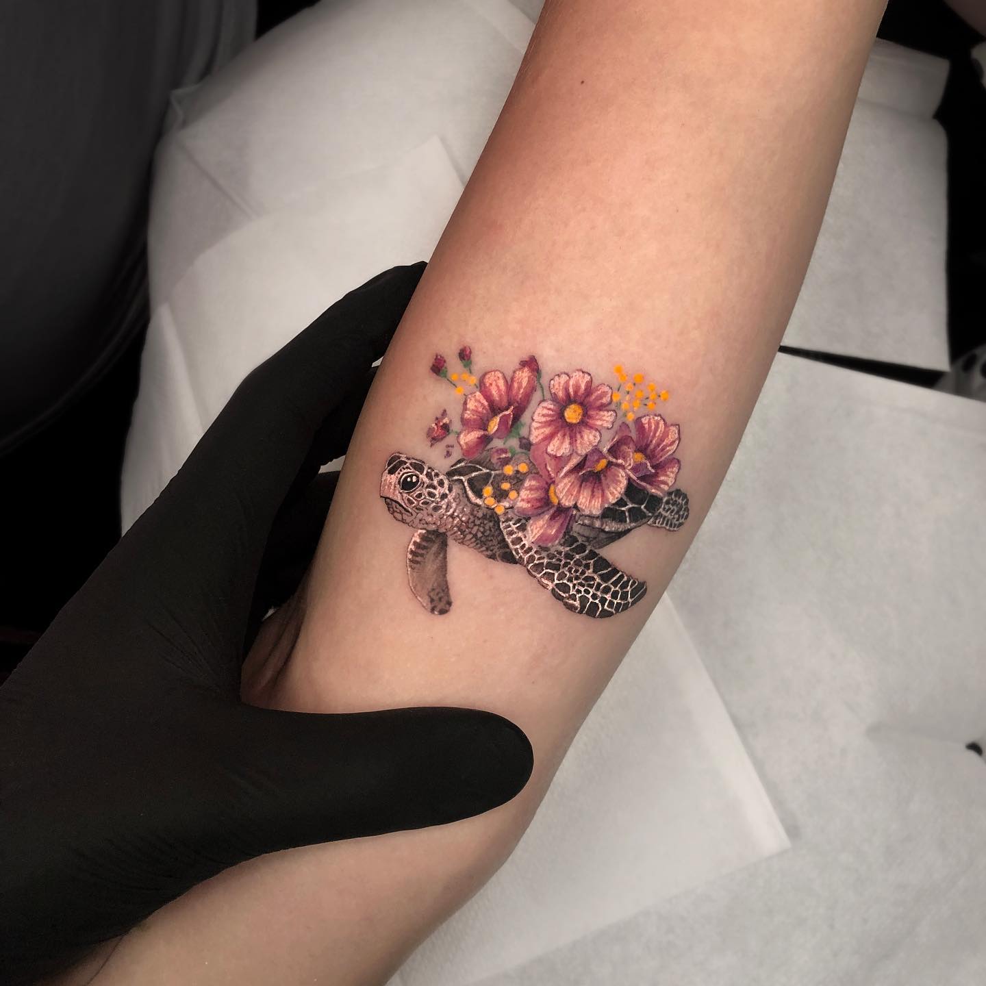 Micro-realistic sea turtle and flowers tattoo on the inner arm