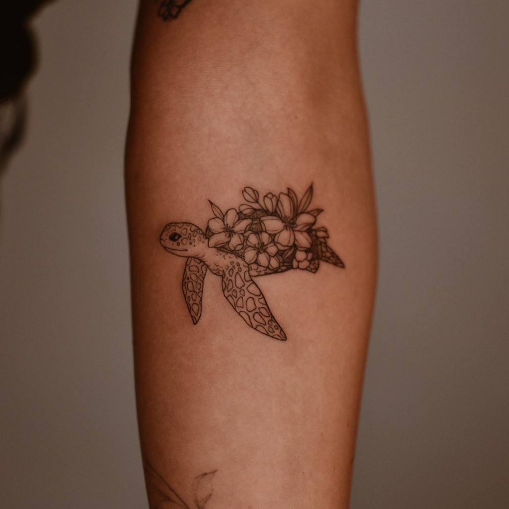 Sea turtle and flowers tattooed on the inner forearm