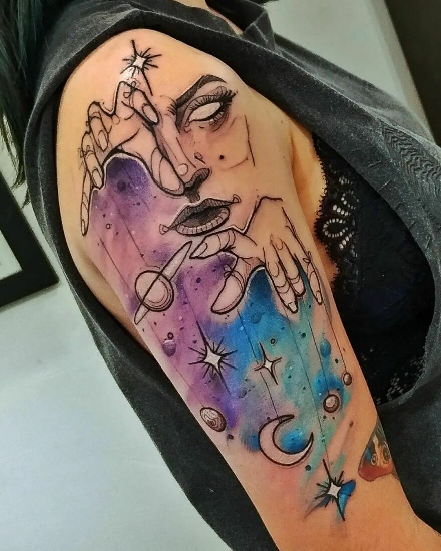 colorful arm tattoo with planets and face with hands