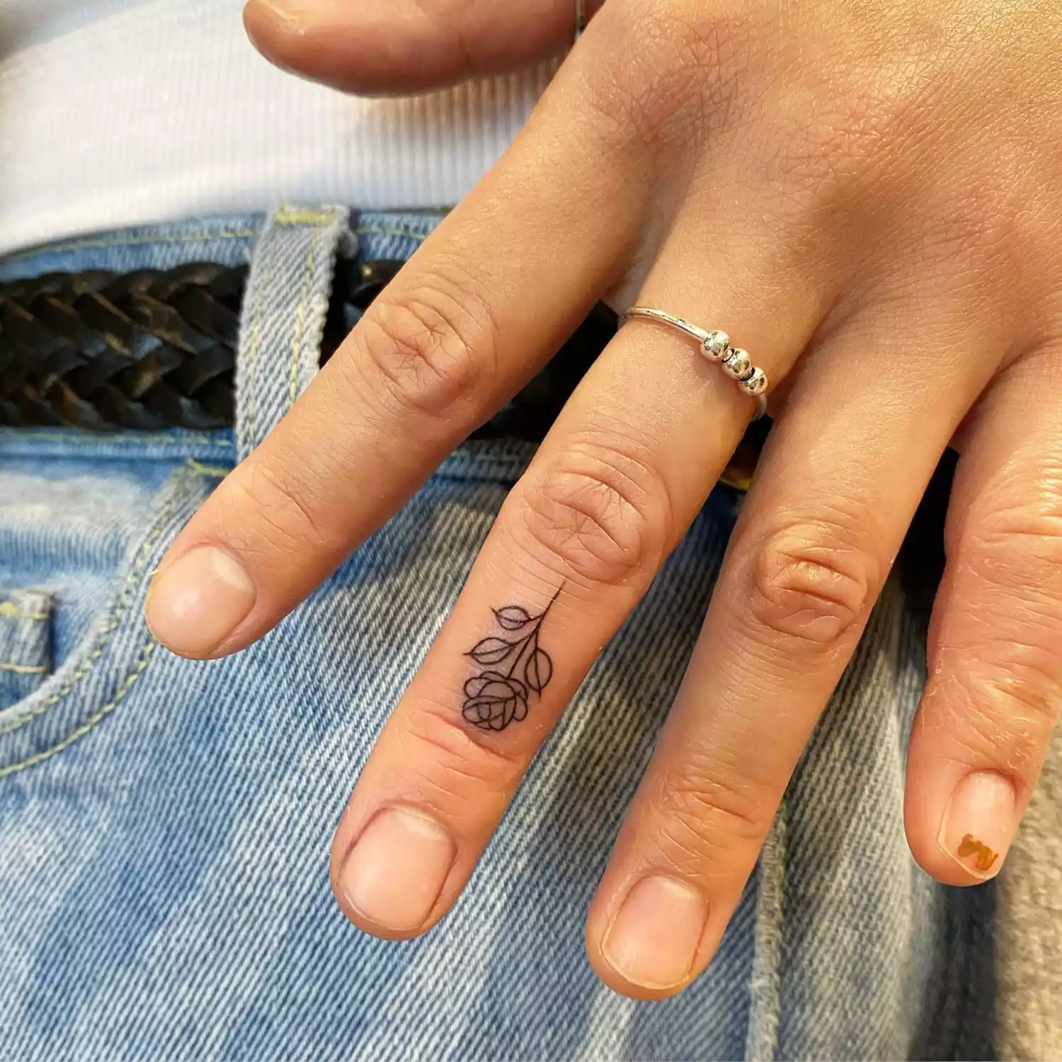 A close up of a rose tattoo on a finger.