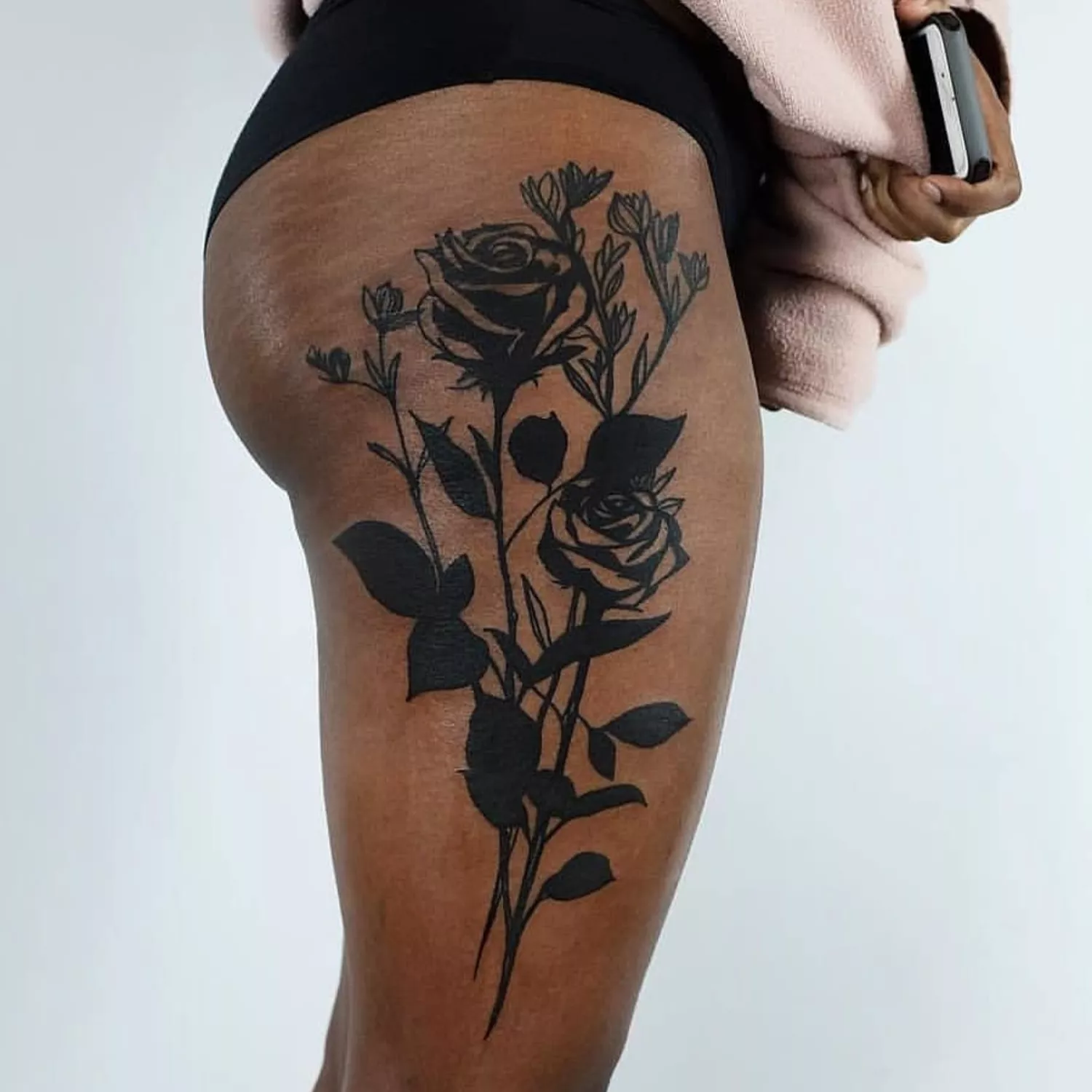 A close up of a rose stem thigh tattoo.