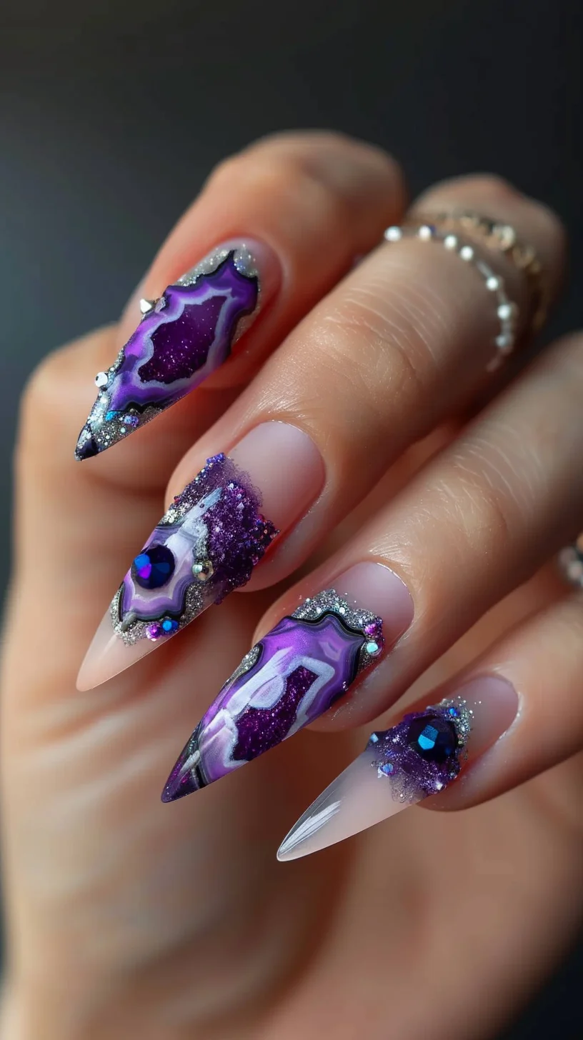 This stunning nail art design combines deep purples and vibrant blue accents, skillfully mimicking the intricate details of geodes. Each nail features a unique pattern, with translucent tips that gradually merge into rich, dark purple, highlighted by silver glitter outlining the geode edges. The addition of sparkling purple crystals and iridescent blue gemstones embedded into the design enhances the depth and realism, creating a 3D effect.