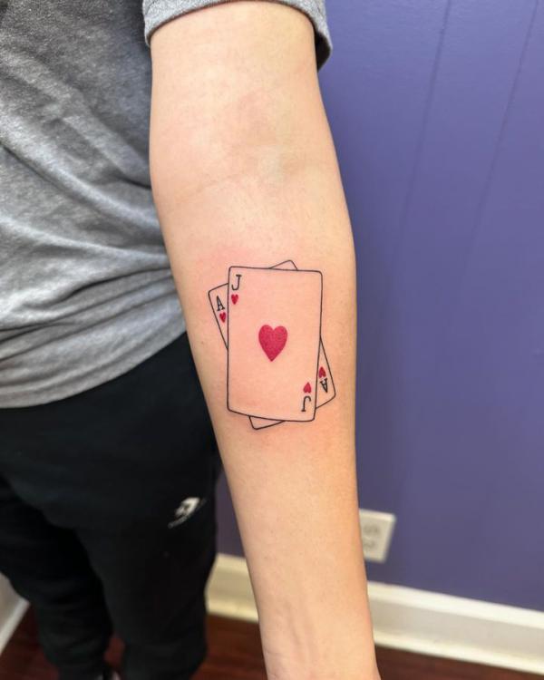 Hearts playing card tattoo on forearm