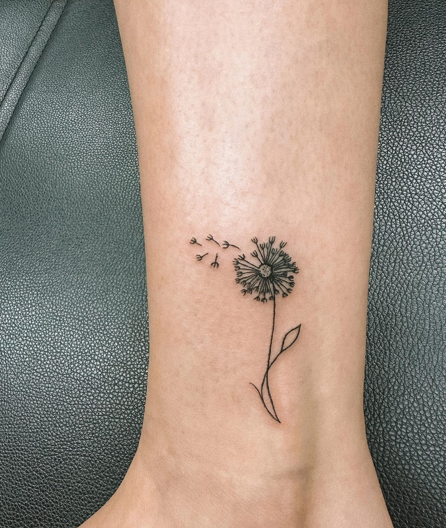 Fine line style dandelion tattoo located on the ankle