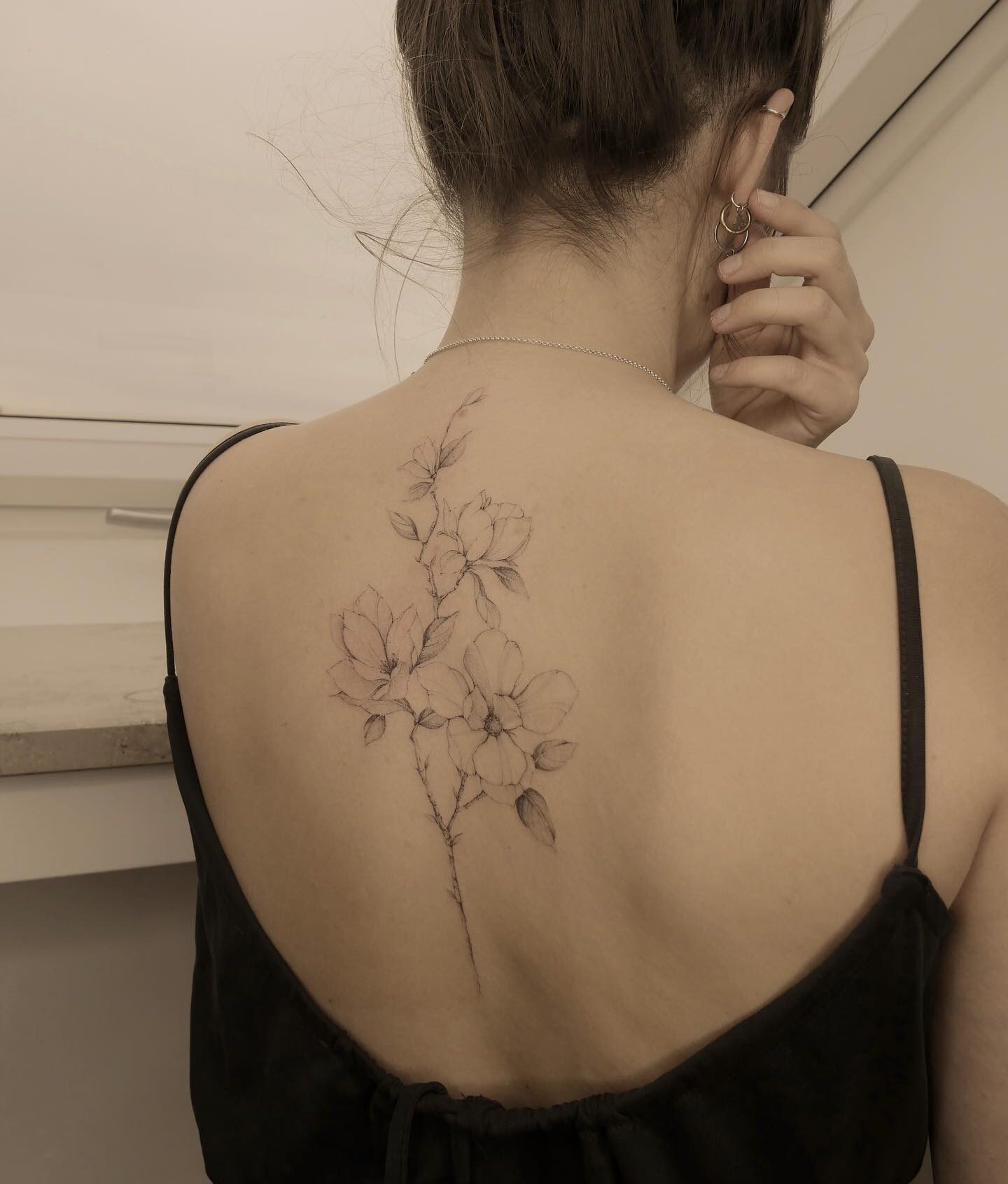 Magnolias tattooed on the back, illustrative style