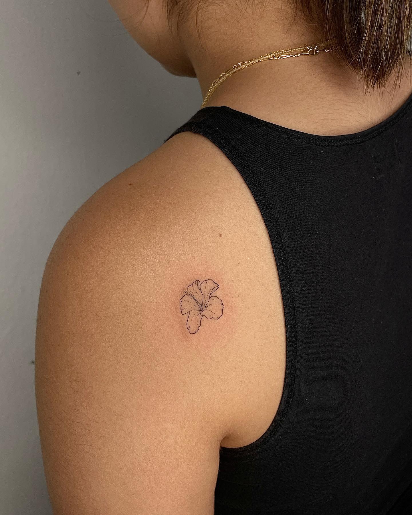 Fine line style hibiscus flower tattoo on the back shoulder