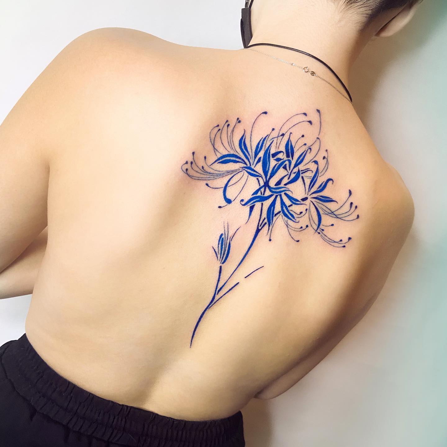 Blue spider lily tattoo located on the back