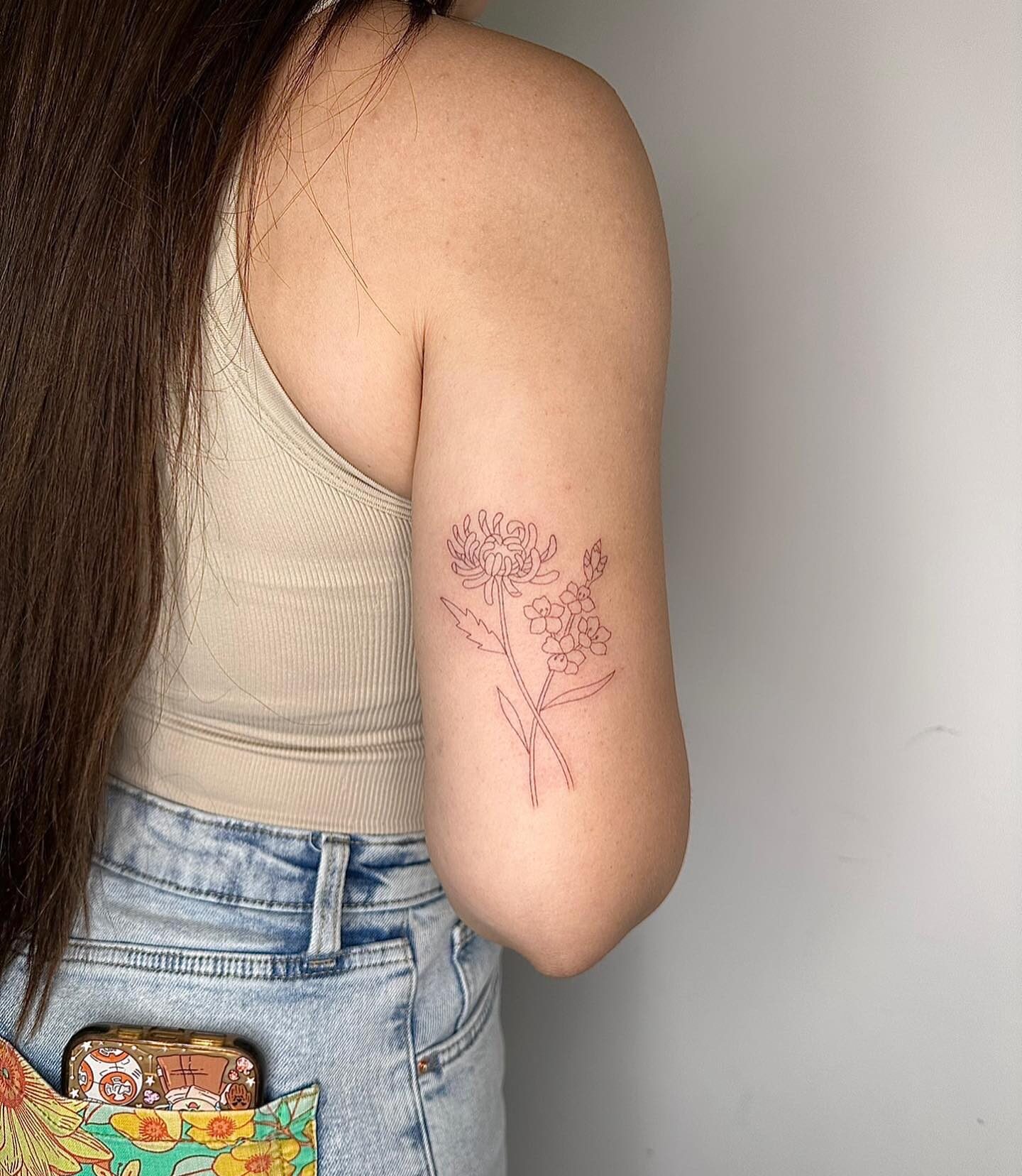 Single needle chrysanthemum and forgot-me-not flowers tattooed on the outer arm